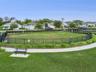 Fenced dog park with an open lawn, seating benches, and surrounding walking paths.