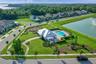 Aerial view of the community pool, playground, and landscaped walking paths beside a scenic pond.