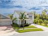 Elevated front view showcasing elegant curb appeal, tropical landscaping, and a two-car garage.