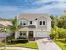 Elevated front view of the two-story home with tropical landscaping and a paver driveway.