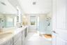 Spacious primary bathroom with a dual-sink vanity, makeup area, and frameless glass shower.