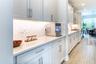 Stylish serving area with white cabinetry, geometric tile backsplash, and under-cabinet lighting.