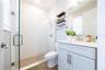Bright bathroom with a frameless glass shower, white tile, mosaic shower floor, and light blue vanity.
