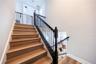 Elegant staircase with warm wood-look finishes and decorative metal railings leading to the upper level.