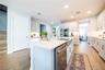 Spacious kitchen island featuring a stainless steel apron-front sink, pull-down faucet, and integrated dishwasher.