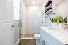 Bright bathroom featuring a frameless glass shower, white tile walls, mosaic shower floor, and a spacious vanity countertop.