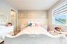 Charming bedroom with decorative wall paneling, patterned wallpaper, and a large window.