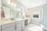 Elegant bathroom with a dual-sink vanity, dressing area, and glass-enclosed shower.