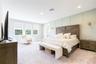 Spacious primary bedroom with an elegant accent wall, sitting area, and porch access with views of a conservation area.