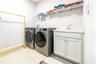 Laundry room with included front-load washer and dryer, utility sink, and storage shelving.