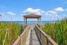 Community boardwalk leading to a covered lakeside gazebo with sweeping water views.