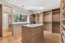 Custom wood-finish cabinetry, built-in shelving, integrated drawers, central island with countertop, and wood-finish flooring