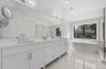 Dual vanity with white cabinetry, polished chrome fixtures, and a large integrated mirror