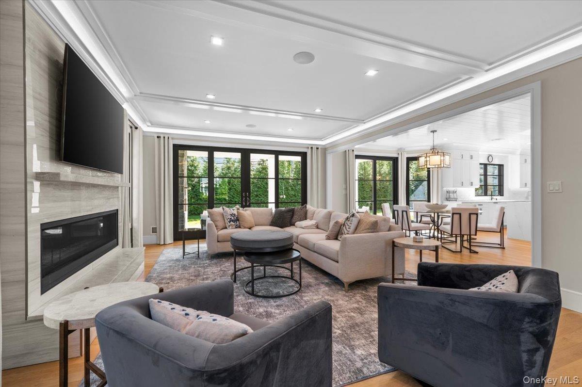 Den with gas fireplace, open concept with view into the kitchen, breakfast room, and backyard