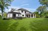 Expansive grass lawn with a covered patio featuring stone columns and Dog Pen
