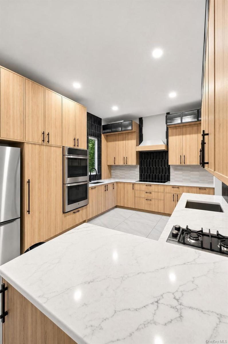 kitchen featuring light wood-finish cabinetry, quartz countertops, stainless steel appliances, and a gas cooktop