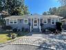Very Pretty Siding exterior with white trim, covered front entry porch, steps with handrails, and a paver stone driveway