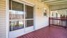 Covered porch featuring a red wood-finish deck and white vinyl siding