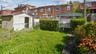 Expansive yard space featuring a storage shed, chain-link fencing, and mature plantings
