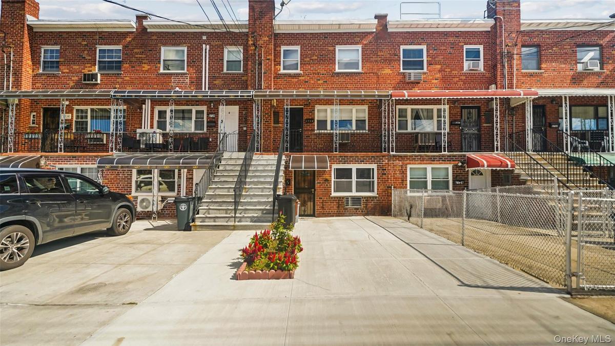 Brick rowhouse with a concrete driveway and an awning-covered entrance