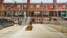 Brick rowhouse with a concrete driveway and an awning-covered entrance