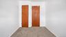 Neutral-toned carpeting paired with white walls, featuring two wood-panel doors