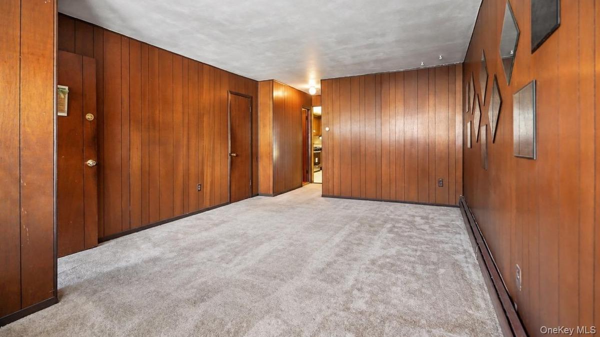 Wall paneling with a rich wood tone, light gray carpeting, and white ceiling finish