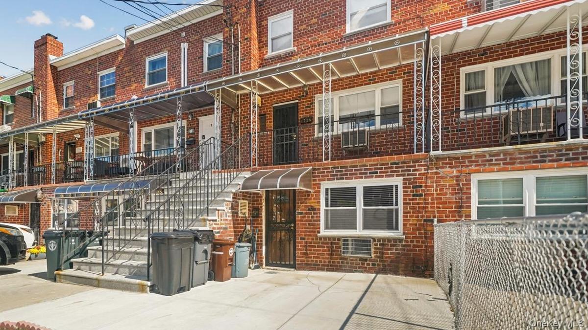 Brick exterior with multiple windows, a covered front entrance, and a chain-link fence