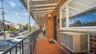 Brick exterior featuring a covered porch with a terracotta tile floor, black metal railing, and white-framed windows