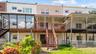 Rear exterior featuring a glass-enclosed sunroom, upper-level deck with awning, wood stairs, and chain-link fencing