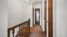 Carpeted hallway with wood doors and a chandelier light fixture