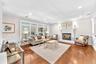 Elegant living room featuring hardwood flooring, a gas fireplace with decorative surround and mantel, recessed ceiling lighting, large multi-pane wind