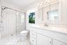 White tiled bathroom featuring a glass-enclosed shower, single vanity