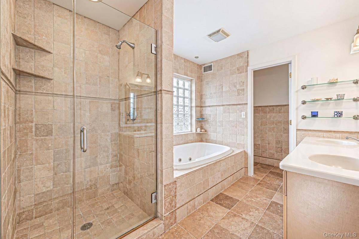 Glass-enclosed shower with tile surround and built-in shelving