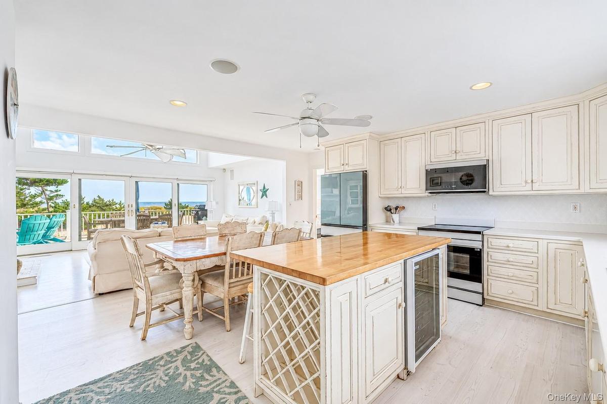 Open-concept kitchen featuring white cabinetry, light wood-finish flooring, a kitchen island with a wood countertop and integrated wine storage, featu