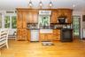 Warm honey-toned cabinetry is complemented by black granite countertops and updated stainless steel and black appliances.
