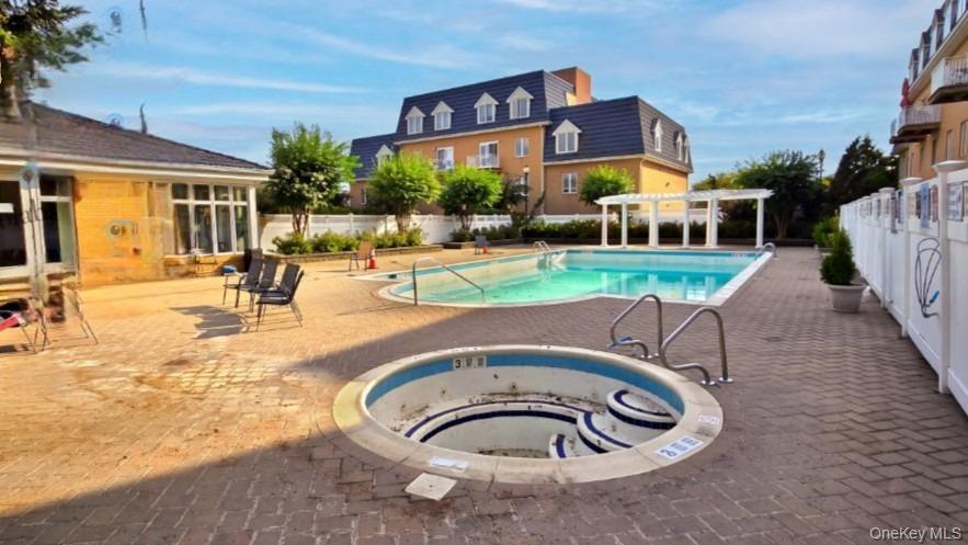 Large outdoor swimming pool, integrated spa, and expansive brick paver patio area