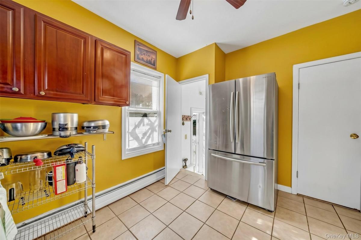 Kitchen featuring tile flooring, wood-finish cabinetry, and a window with blinds