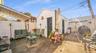 Expansive concrete patio area with a white picket fence, covered patio section, and a standalone storage structure