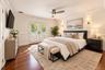 Hardwood flooring, crown molding, double French doors with interior shutters, wall-mounted sconces, and a ceiling fan with integrated lighting