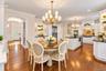 Spacious open-concept kitchen with wood-finish flooring, white cabinetry, dark countertops, and a central island with a sink