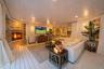 Spacious open-concept living area featuring a wood-burning fireplace with stone surround, wide-plank wood-finish flooring, coffered ceiling with reces