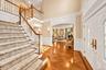 Grand foyer featuring a dual-level staircase with white balusters and wood handrails, herringbone wood flooring, decorative wall molding, and arched d