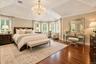 Tray ceiling with a crystal chandelier, wood-finish flooring, and a bay window