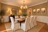 Elegant formal dining room showcasing damask-patterned wallcovering, wainscoting with crown molding, hardwood flooring, and a multi-arm brass chandeli