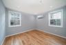 Unfurnished room featuring light wood-type flooring, plenty of natural light, and a wall mounted air conditioner