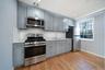 Kitchen featuring appliances with stainless steel finishes, gray cabinetry, decorative backsplash, and light stone countertops