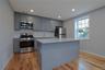 Kitchen featuring gray cabinetry, stainless steel appliances, tasteful backsplash, a kitchen island, and light wood-type flooring