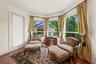 Private primary sitting area featuring rich hardwood floors, expansive windows framing outdoor views, and elegant drapery.