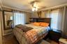 The primary bedroom features natural light from multiple windows and a ceiling fan.